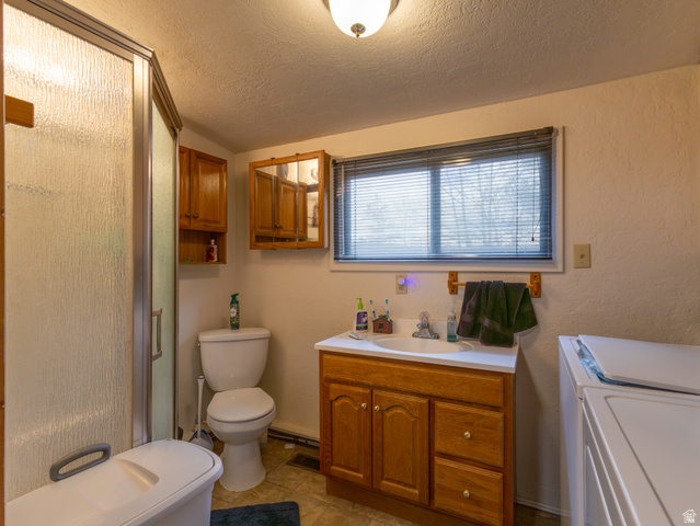 5082 Pine Crest Road Evanston, UT 82930 - Photo 16 of 25 Bathroom featuring a glass-enclosed shower, a vanity with wood-finish cabinetry, a window with blinds, and tile flooring