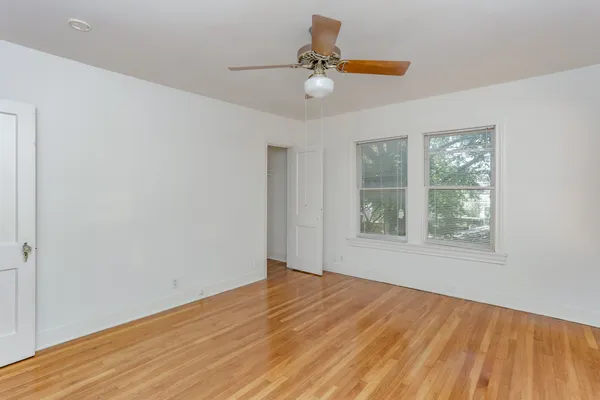 a view of an empty room with a window and wooden floor