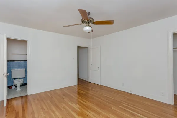 a view of empty room with wooden floor and ceiling fan