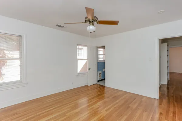 a view of empty room with wooden floor and fan