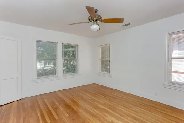 a view of an empty room with a window and wooden floor