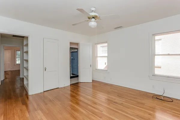 an empty room with wooden floor and windows