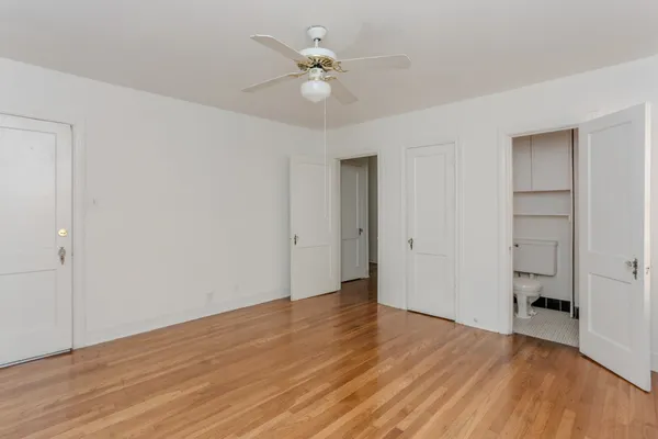 an empty room with wooden floor and ceiling fan
