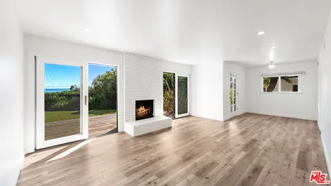 a view of empty room with wooden floor and fireplace