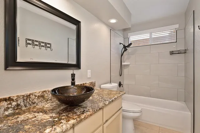 a bathroom with a granite countertop sink a toilet and shower