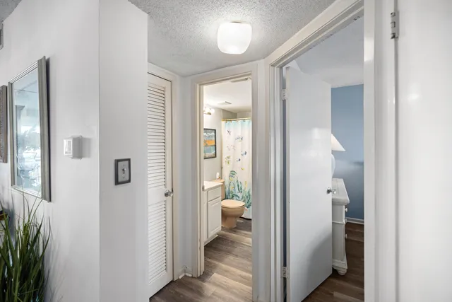 a view of a hallway with wooden floor and a bathroom