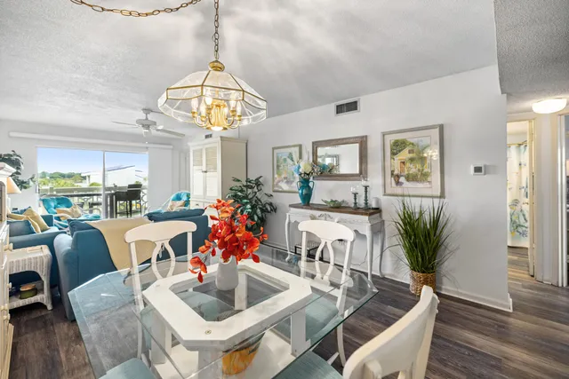 a dining room with wooden floor a chandelier a glass table and chairs