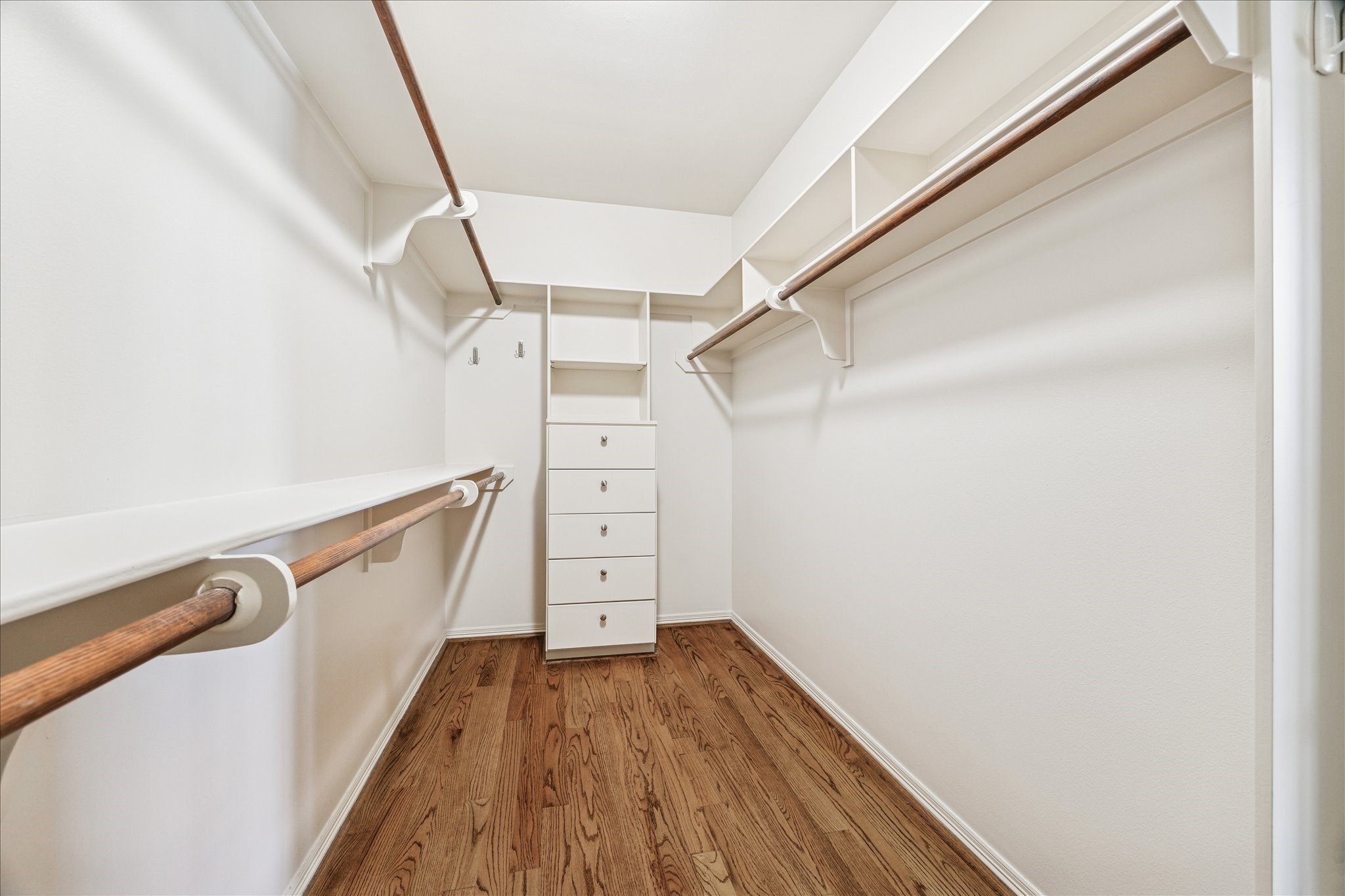 5823 Augusta Court Houston, TX 77057 - Photo 37 of 44 Spacious walk-in closet with hardwood floors, multiple hanging rods, and built-in drawers for ample storage.