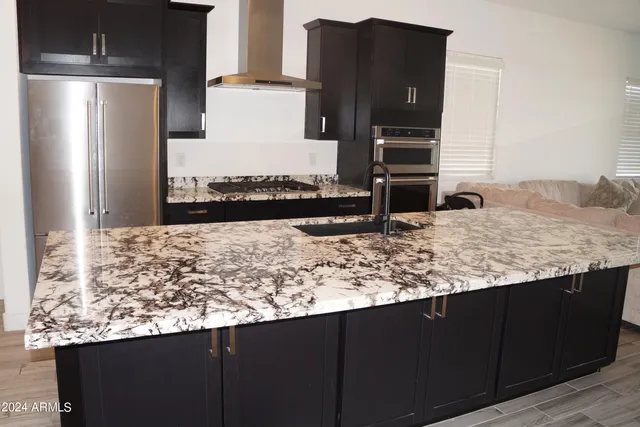 a kitchen with kitchen island granite countertop a refrigerator and a sink