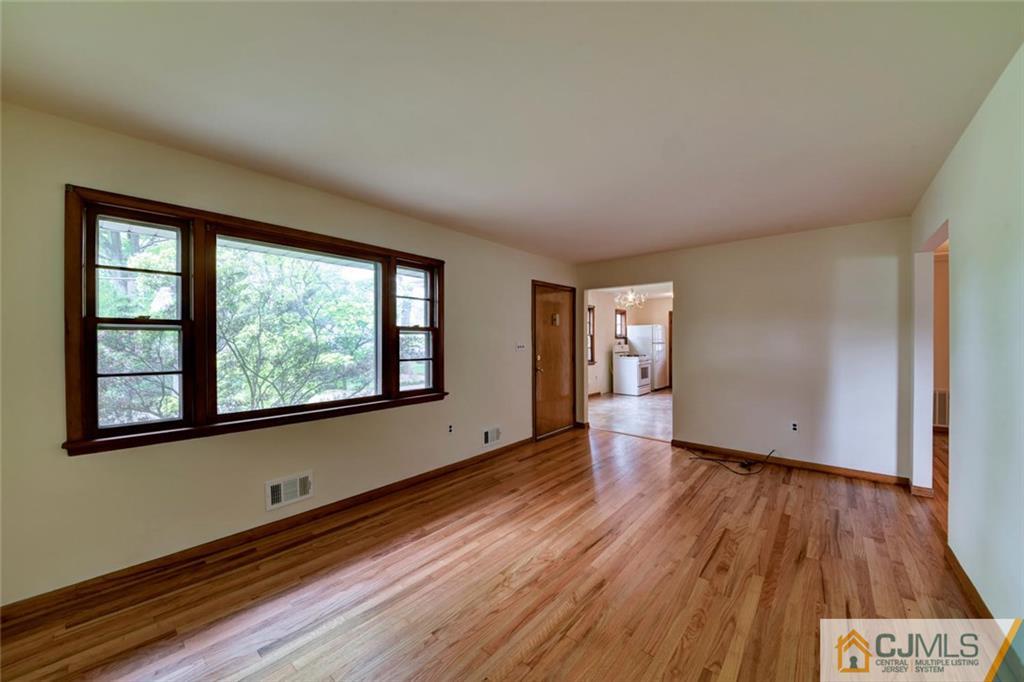 65 Long Hill Road Colonia, NJ 07067 - Photo 5 of 16 a view of an empty room with wooden floor and a window