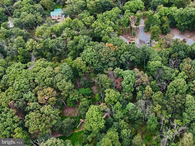 an aerial view of residential house with outdoor space and trees all around