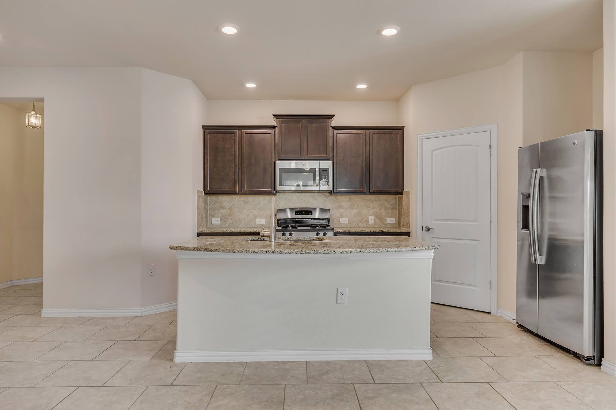 7212 Vail Ridge Street Austin, TX 78744 - Photo 4 of 26 A well-appointed kitchen features rich cabinetry, granite countertops, and modern stainless-steel appliances.