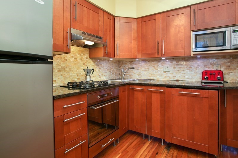 130 Sutherland Road, Unit 11 Boston, MA 02135 - Photo 2 of 7 a kitchen with stainless steel appliances granite countertop wooden cabinets and a stove top oven