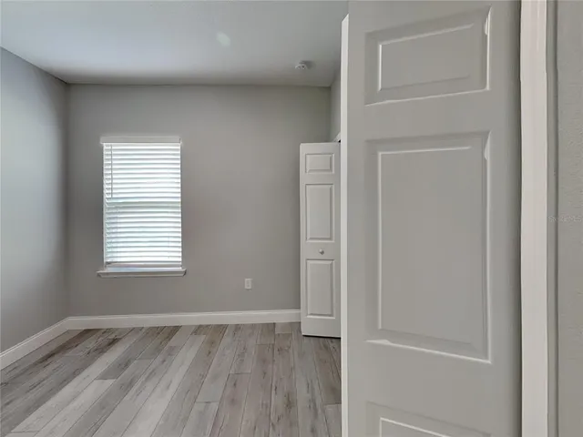 an empty room with wooden floor and window