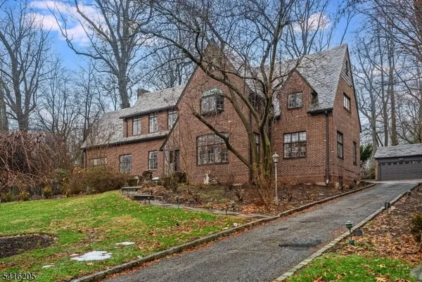 a view of a brick house next to a yard with large trees