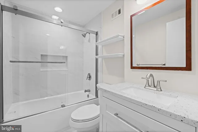 a bathroom with a granite countertop shower sink vanity mirror and toilet