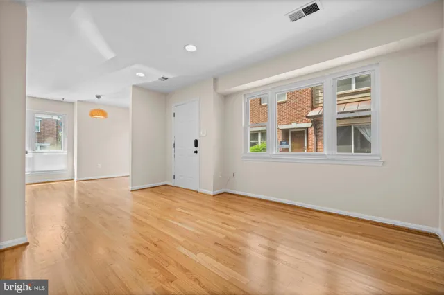 a view of empty room with wooden floor and fan