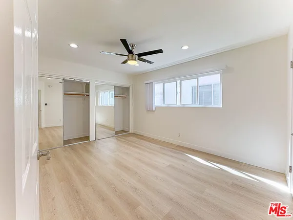 a view of empty room with wooden floor and ceiling fan