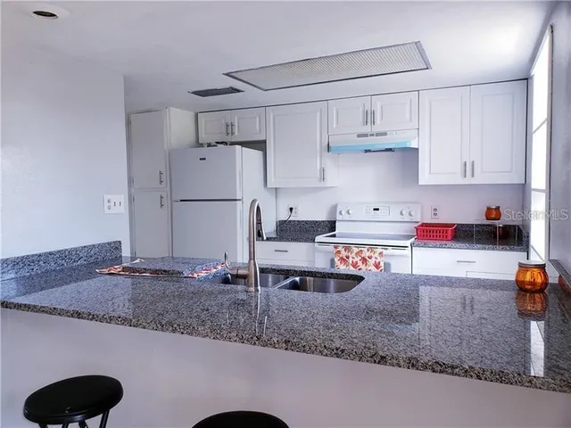 a kitchen with stainless steel appliances granite countertop a sink refrigerator and cabinets