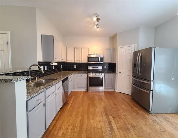 a large kitchen with a sink stainless steel appliances and cabinets