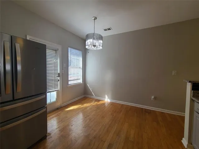 an empty room with wooden floor cabinet and windows
