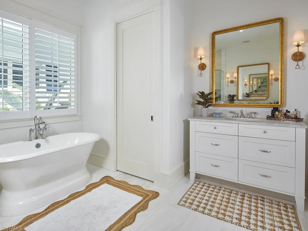 909 10th Avenue South Naples, FL 34102 - Photo 18 of 34 a bathroom with a sink a mirror and a bathtub
