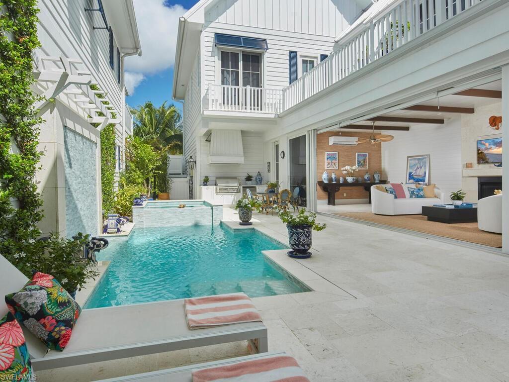 909 10th Avenue South Naples, FL 34102 - Photo 29 of 34 a view of a patio with table and chairs potted plants and palm trees