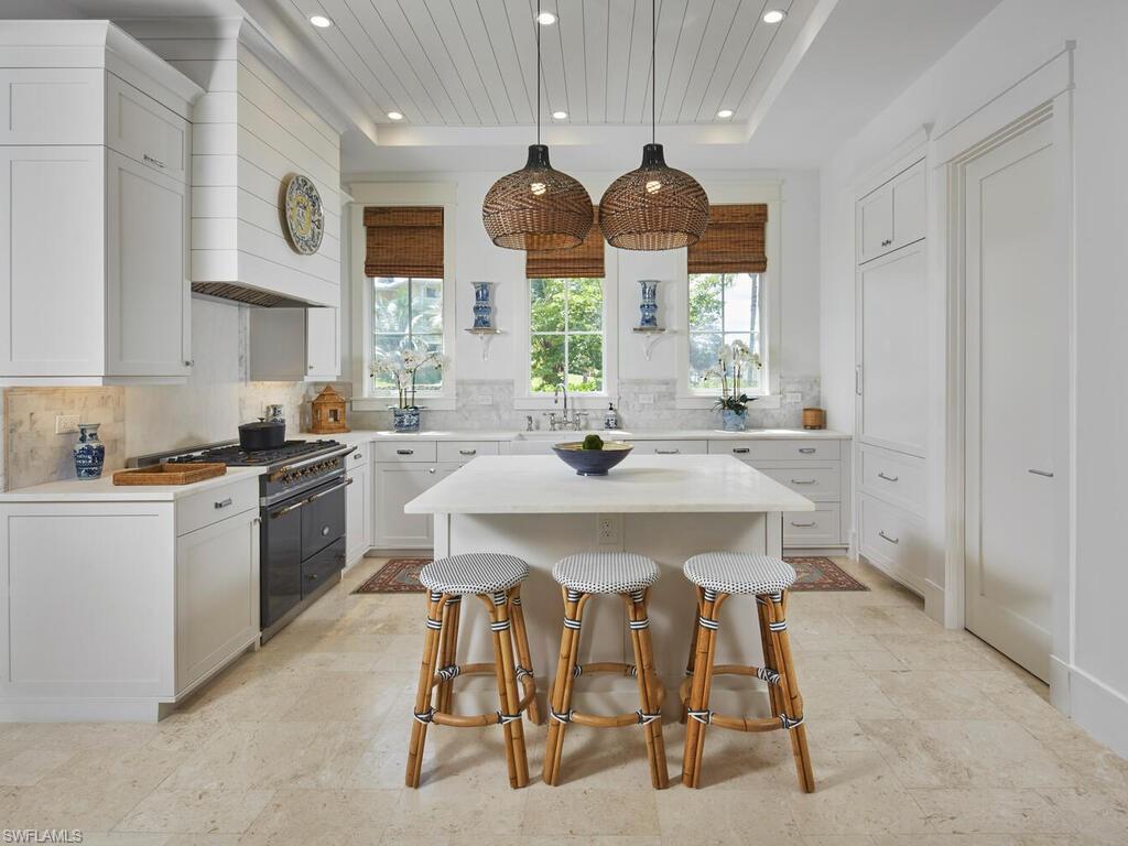 909 10th Avenue South Naples, FL 34102 - Photo 7 of 34 a kitchen with stainless steel appliances kitchen island granite countertop a sink a stove a dining table and chairs