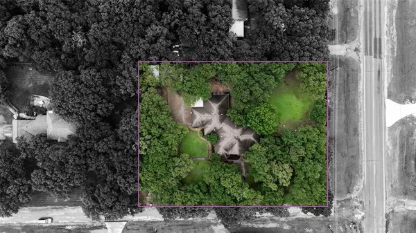 an aerial view of residential house with outdoor space and trees all around