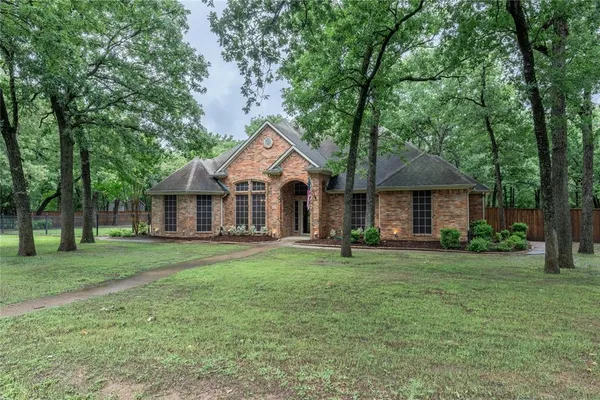 a front view of a house with a garden and trees