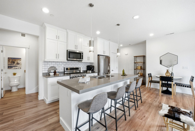 3355 Santa Fe Road Park City, UT 84098 - Photo 5 of 45 Open-concept kitchen featuring white shaker cabinetry, stainless steel appliances, a subway tile backsplash, and a large island with counter seating