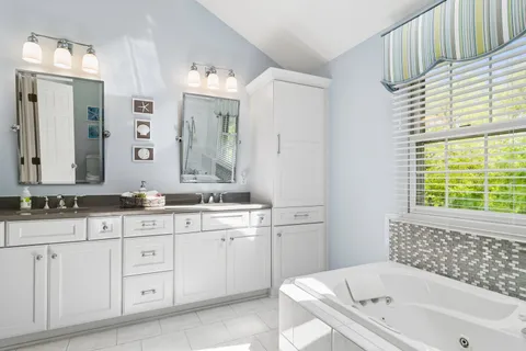 a bathroom with a tub a sink and a large mirror