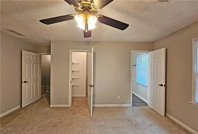 an empty room with closet and a ceiling fan