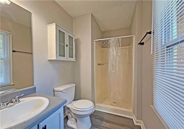 a bathroom with a granite countertop sink toilet a mirror a vanity and shower