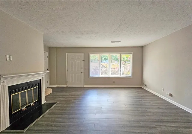 an empty room with wooden floor fireplace and windows