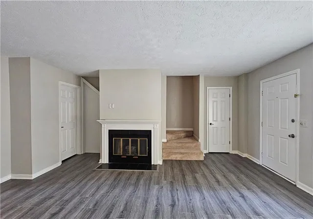 a view of an empty room with wooden floor fireplace and a window