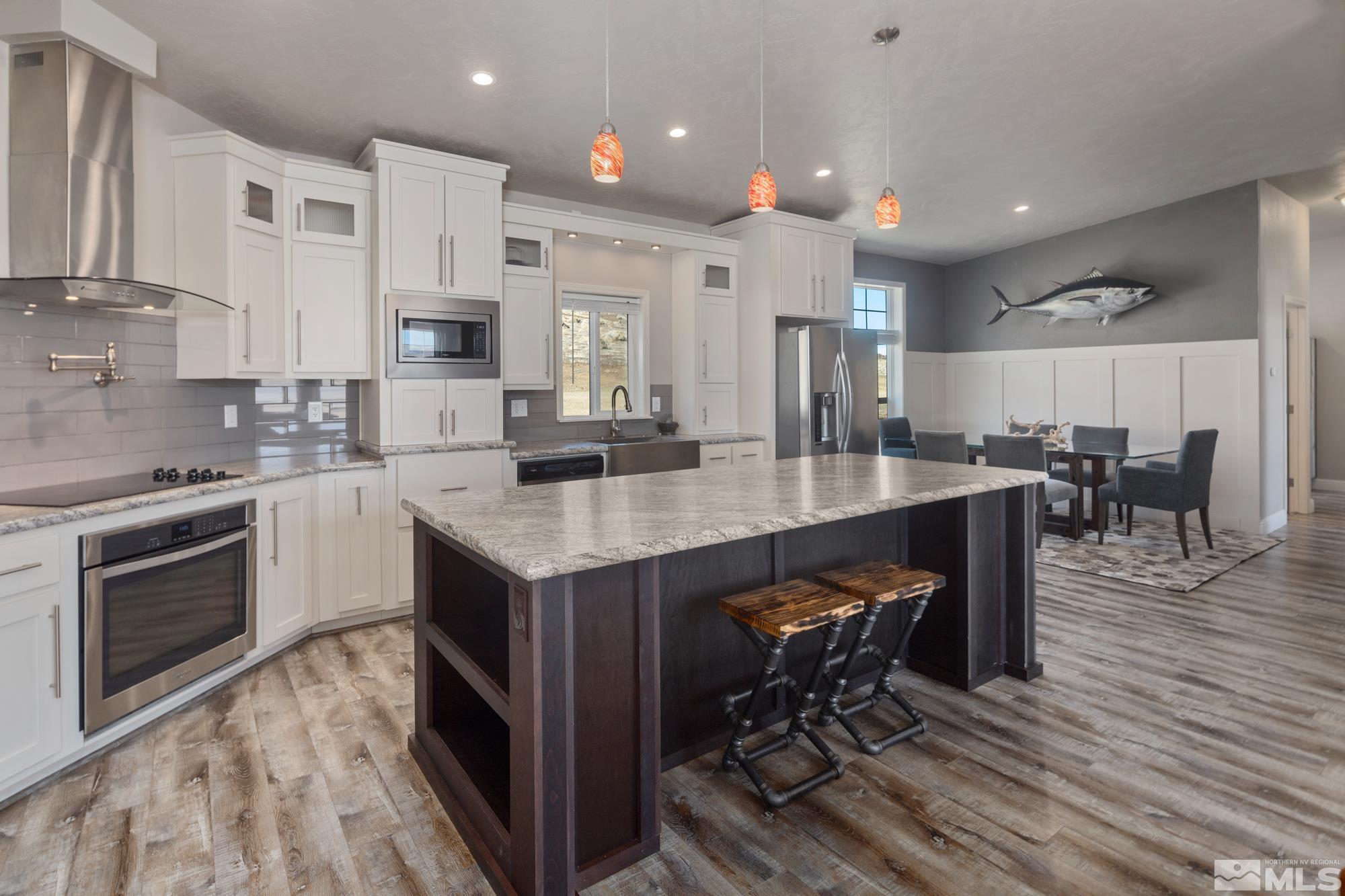 900 Ironwood Road Reno, NV 89510 - Photo 8 of 40 a kitchen with stainless steel appliances granite countertop a stove top oven a sink dishwasher a dining table and chairs with wooden floor