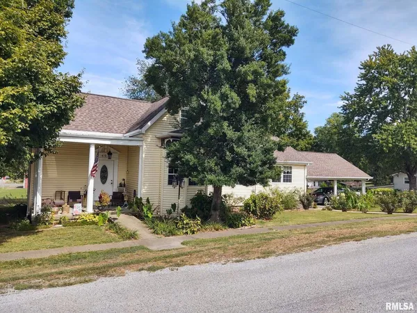 a front view of a house with garden and trees