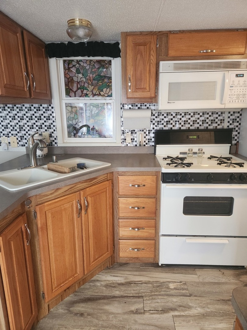 24-65 Woodhaven Lakes Sublette, IL 61367 - Photo 17 of 32 a kitchen with granite countertop a stove a sink and a microwave