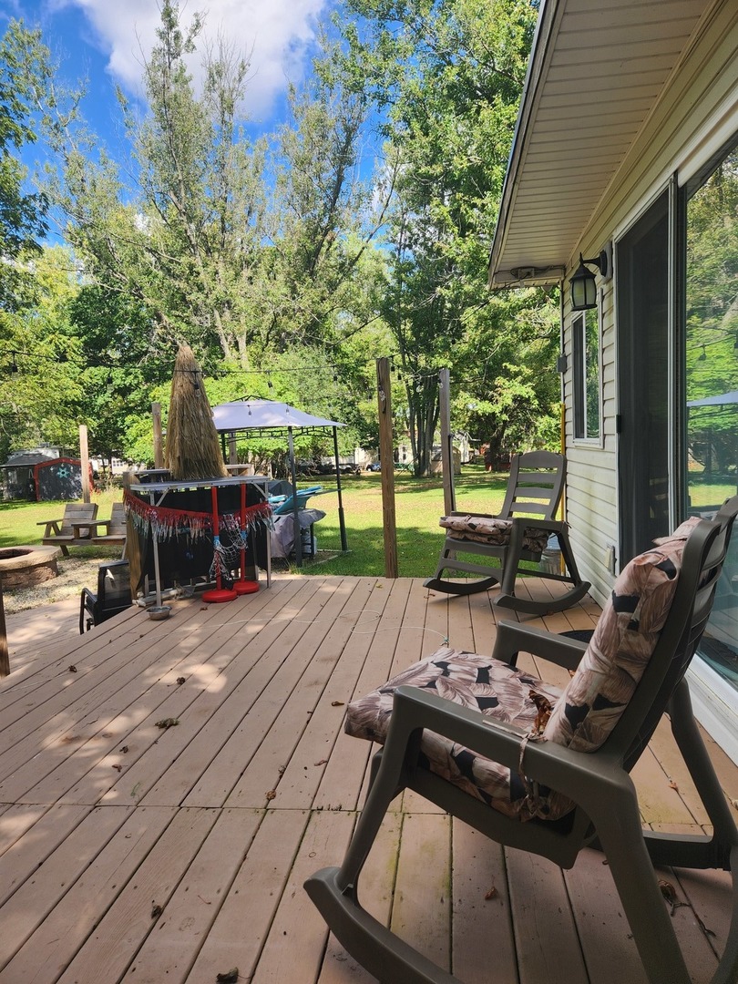 24-65 Woodhaven Lakes Sublette, IL 61367 - Photo 5 of 32 a view of a patio with table and chairs under an umbrella with a small yard