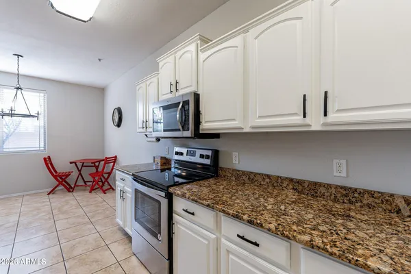 a kitchen with stainless steel appliances granite countertop a stove a sink and a white cabinets