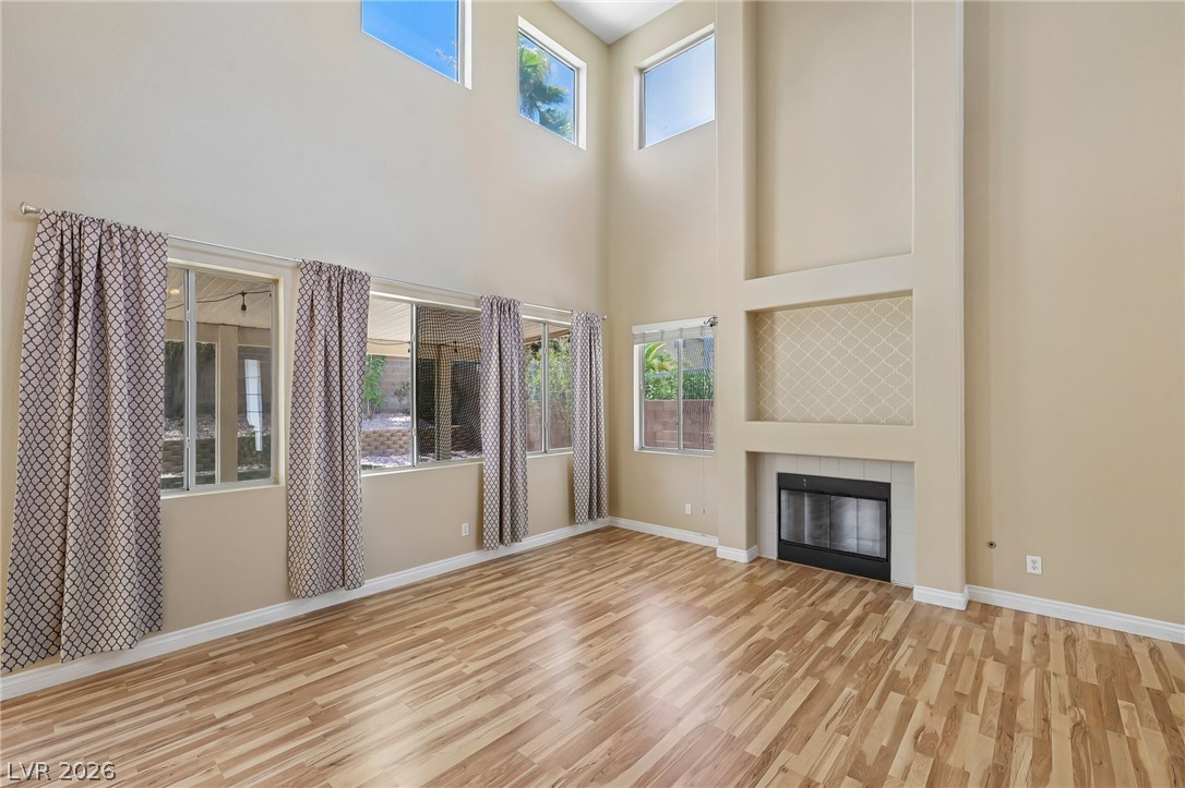 1727 Millstream Way Henderson, NV 89074 - Photo 12 of 46 A soaring living room with high ceilings, a cozy fireplace, and rich wood flooring.