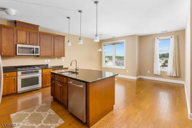 a kitchen with stainless steel appliances granite countertop a kitchen island a stove a sink and a microwave