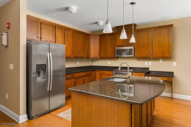 a kitchen with stainless steel appliances granite countertop a sink a refrigerator and a granite counter tops