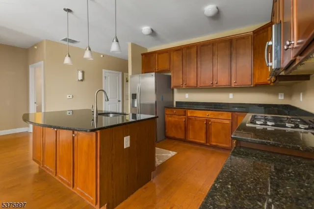 a kitchen with stainless steel appliances granite countertop a sink a stove and a refrigerator
