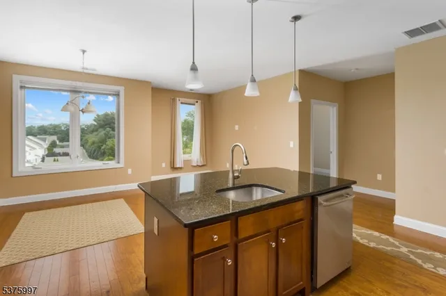 a kitchen with stainless steel appliances granite countertop a sink a center island and a wooden floor