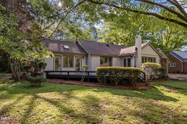 a front view of a house with a garden and trees