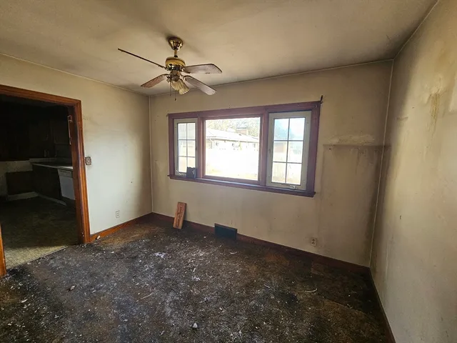 an empty room with windows and fan