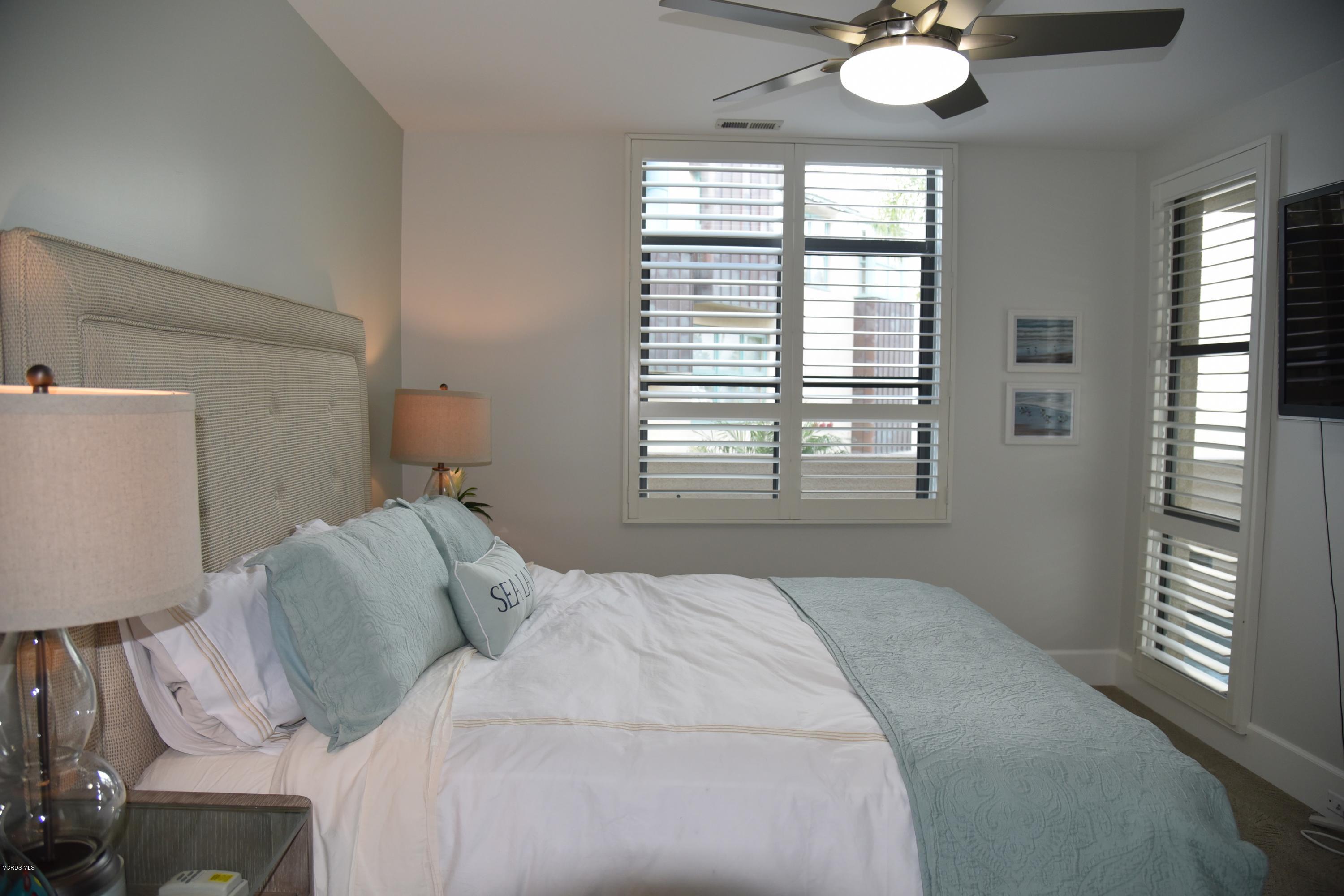 4885 Sandyland Road, Unit 2 Carpinteria, CA 93013 - Photo 23 of 39 a bedroom with a bed and a chandelier
