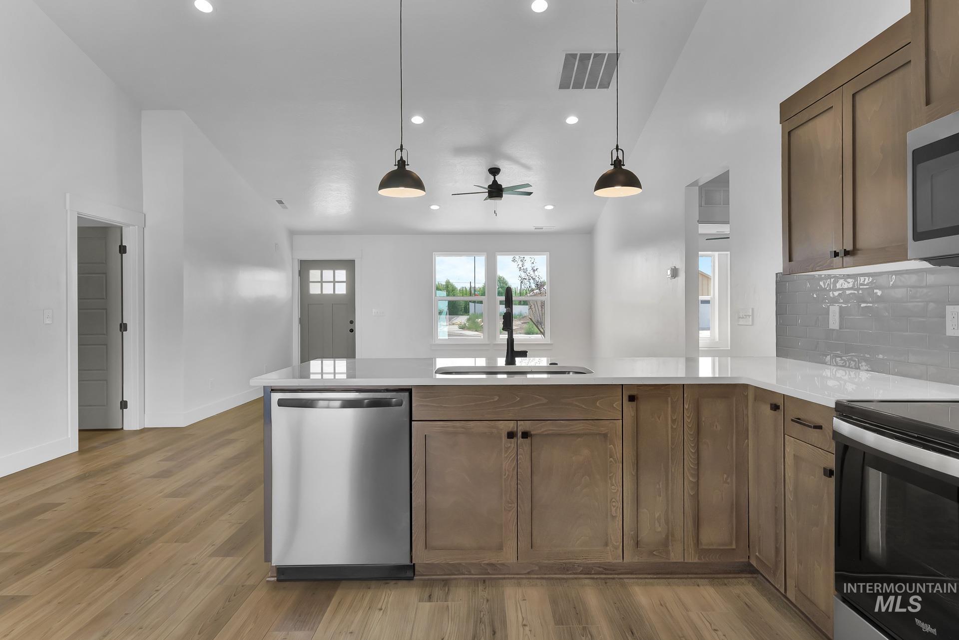 1160 Velvet Loop Wilder, ID 83676 - Photo 10 of 29 Kitchen with stainless steel appliances, a peninsula, recessed lighting, light stone counters, and decorative light fixtures